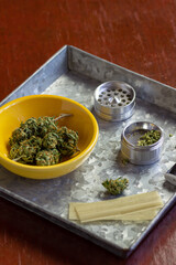 Grinding Marijuana Buds or Hemp Flowers to Fill Rolling Papers in Metal Tray with Smoking Accessories