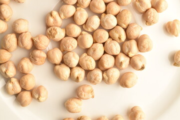 Uncooked hummus grains, close-up, on a white wooden table.