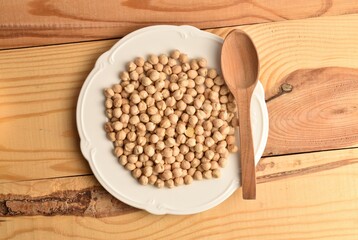 Uncooked hummus grains, close-up, on a wooden table.