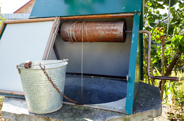 Old draw-well in European village. Retro stone water well in rural area