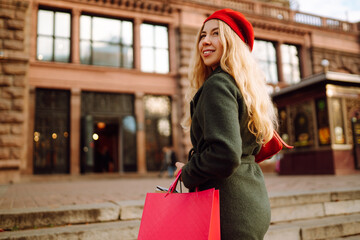 Stylish young modern woman in trendy clothes with colorful shopping bags is walking on the street after shopping. Autumn shopping. Black friday.