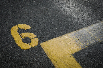 sign on the asphalt, yellow painted number six on grey street, yellow lines like a corner on the...