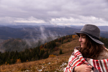 Girl traveler in the mountains in boho clothes with a hat. Enjoys nature and travel. Local camping concept. Copy space