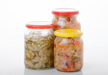 Glass jars of pickled homemade organic cucumber carrrot with garlic and red cabbage vegetables  isolated on white background 
