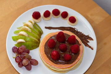 Pancakes mit Obst und Nutella oder Sternen auf einem Teller angerichtet Bunt