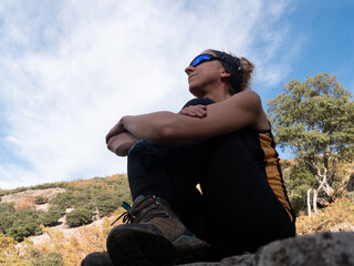 BLOND WOMAN HIKING WITH GLASSES, SITTING IN THE MOUNTAIN