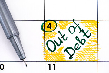 Reminder Out of Debt in calendar with pen.