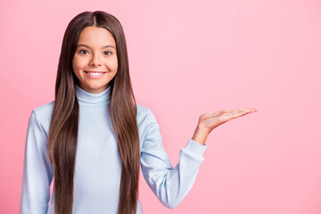 Portrait of beautiful pupil girl arm palm show empty space banner choice isolated on pastel pink color background