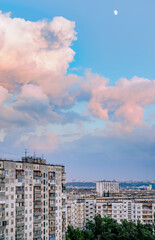 Fototapeta na wymiar High buildings in the Obolon district of Kiev, Ukraine, near the Minska metro station. Big pink clouds in the sky, and the Moon