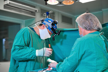 Surgeon and his assistant performing cosmetic surgery on nose in hospital operating room. Nose...