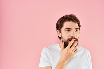 Man in white t-shirt gestures with hands emotions lifestyle cropped view pink background