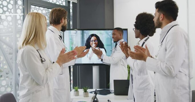 Beautiful Smiling Black-skinned Doctor Greeting Her Diverse Medical Team With Right Get Decision During Online Conference And Rewarding Applause Each Other