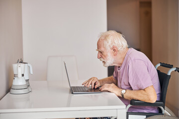 Male pensioner writing an email on his computer