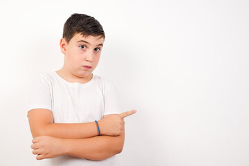 Caucasian young boy standing against white background  smiling broadly at camera, pointing fingers...