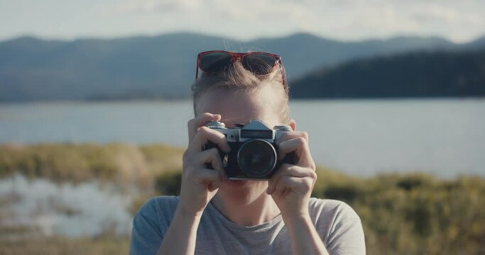 Blonde woman take analog photo look camera at lake close up portrait	