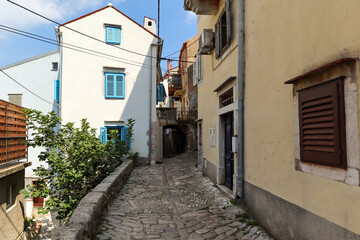 Apartment houses and footpath in the town of Vrbnik on the island of Krk, old historical buildings in summer, Croatia Europe
