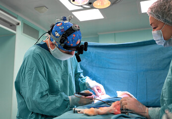 Surgeon and his assistant performing cosmetic surgery on nose in hospital operating room. Nose...