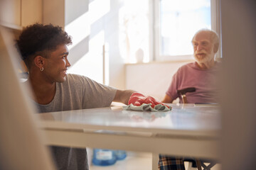Dark-haired volunteer cleaning the disabled man kitchen