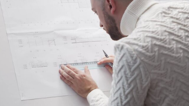 Concentrated architect works in loft using drawing board. Workplace of young engineer in modern office.