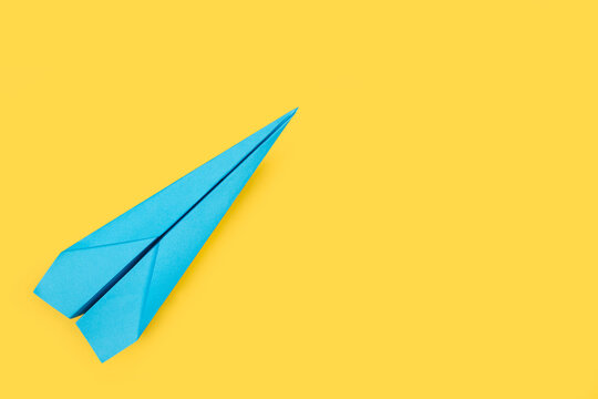 Avi&oacute;n de papel azul sobre fondo amarillo liso y aislado. Vista superior. Copy space