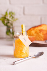 A jar of orange jam and a cake on a white table