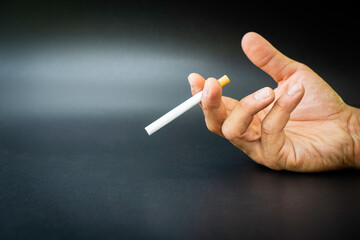 Hand of a man who grabs a cigarette without light, World No Tobacco Day concept