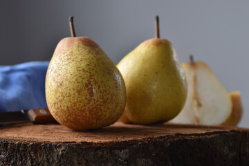 fresh whole and halved pears on rustic wood on blue background. selective focus. horizontal.