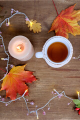 beverage, hot drink in a mug, leaves, foliage, garland, candles, top view of wooden table, good weather concept, outdoor tea party, cozy autumn mood