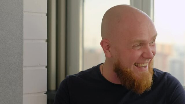 Young bald European man with red beard laughs loudly into the camera. Close-up. Positive emotions.