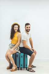 Nice couple sitting on suitcase looking delighted.