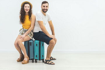 Loving young couple waiting for flight at airport and sitting on suitcase.