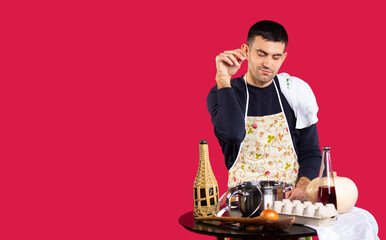 Young man pour salt and seasoning into a saucepan. Photo on a pink background with empty side...
