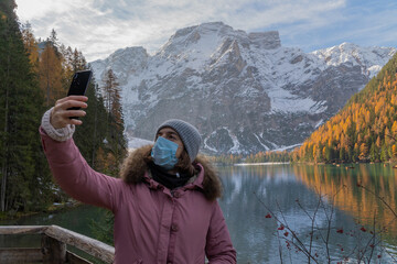 A woman who is having her photo taken with a lake and mountains in the background.