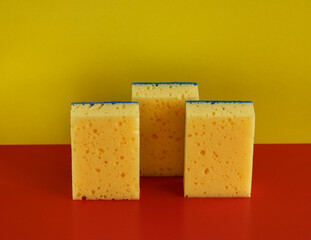 Big yellow cleaning sponges on red and yellow background high angle view