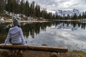 A woman looking at the lake with some mountains in the background.