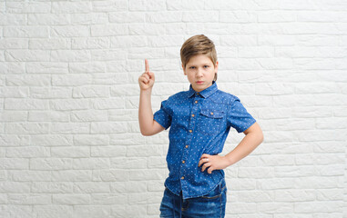 Cute 9 year-old european race boy with one hand pointing to empty space upward isolated on light  background