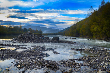 Beautiful landscape with high mountains with illuminated peaks, stones in mountain lake, reflection, blue sky and sunrise. HDR