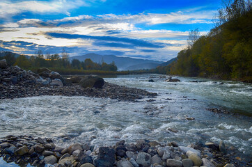 Beautiful landscape with high mountains with illuminated peaks, stones in mountain lake, reflection, blue sky and sunrise. HDR