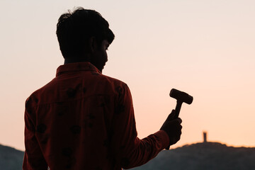 Fototapeta na wymiar Silhouette of an Indian kid holding hammer