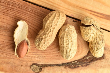 Unpeeled organic peanuts, close-up, on a wooden table.
