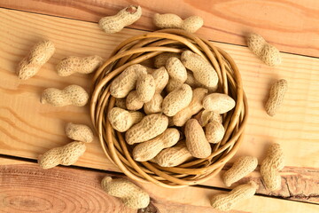 Unpeeled organic peanuts, close-up, on a wooden table.