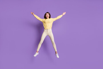 Fototapeta na wymiar Full length photo portrait of excited girl jumping up spreading arms legs like star isolated on vivid violet colored background