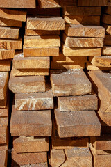 Roughly processed boards lie in a stack. Close-up view of the ends of the boards. Softwood lumber in a stack in the sun.