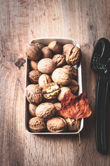 Ganze Walnüsse in einer Schüssel und ein Nussknacker mit einem orangen Herbst Blatt auf einem rustikalen Holztisch. Nahaufnahme, gesunde Ernährung, Protein.