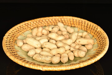 Unpeeled organic peanuts, close-up, on a black background.