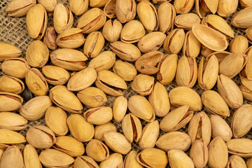 Salted pistachios lie on the burlap. Close up.