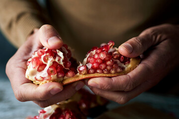 man opening a pomegranate fruit