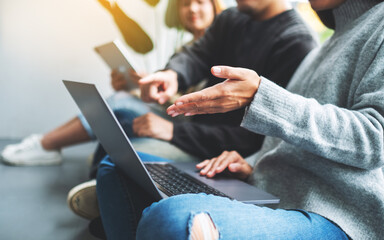 A group of young people sitting and using laptop computer and digital tablet together
