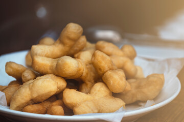 Patongko or deep-fried dough sticks, traditional morning snack or breakfast of Thai and Chinese, close up Patongko or deep-fried dough sticks in white plate.