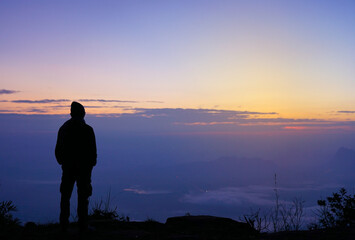 Selective focus of men's silhouette alone looking at the sunrise nature view with beautiful color background